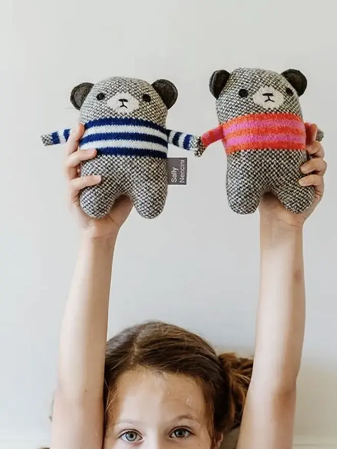 young girl holding two bear plushes above her head
