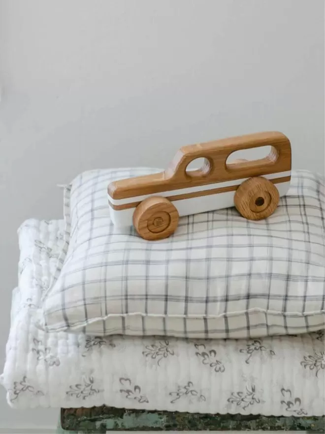 Wooden Toy Car Station Wagon in White resting on a pile of pillows