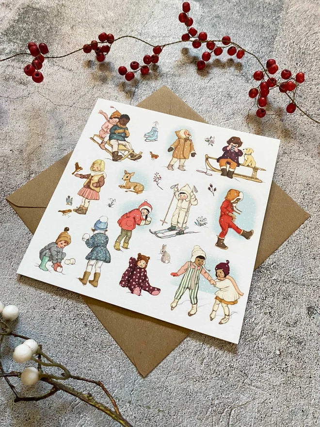 An illustrated Christmas greeting card featuring little children playing in the snow