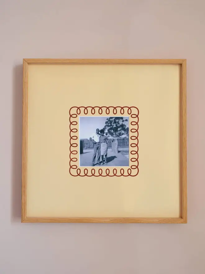 The frill instax square mount frame with a mount featuring a decorative frill border around a centered Instax Square photo, displayed on a neutral beige wall.