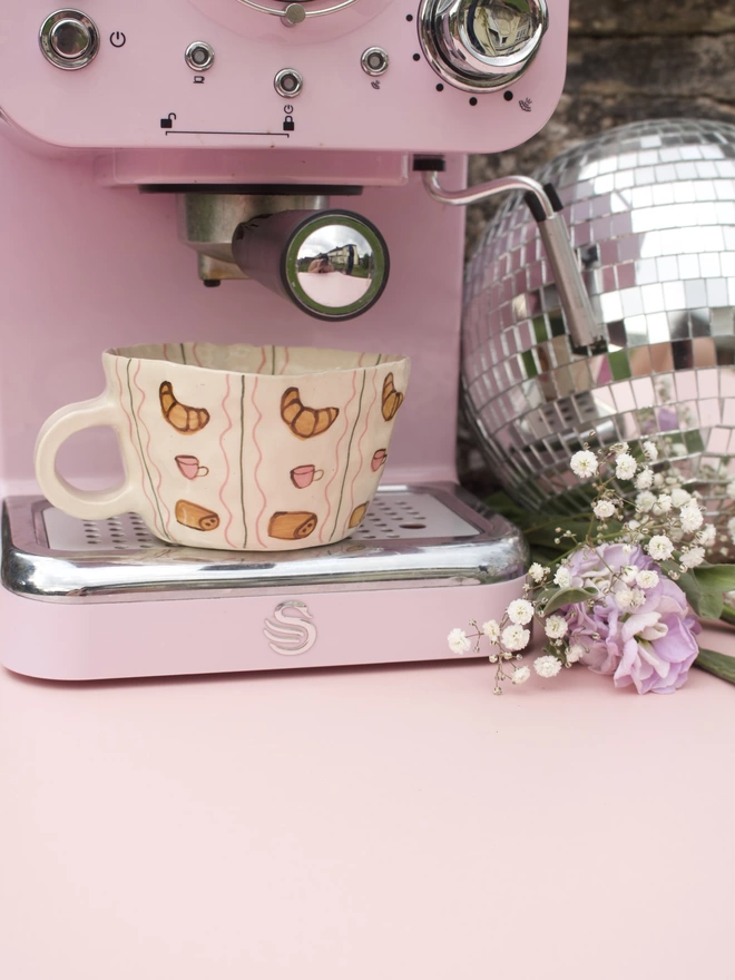 handmade stoneware mug decorated with handpainted croissants, coffee cups and pain au chocolat in a striped pattern