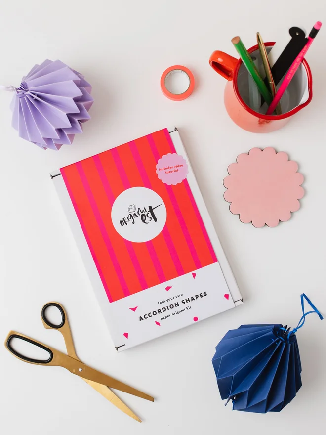 Craft kit on a table surrounded by craft materials and paper ornaments.