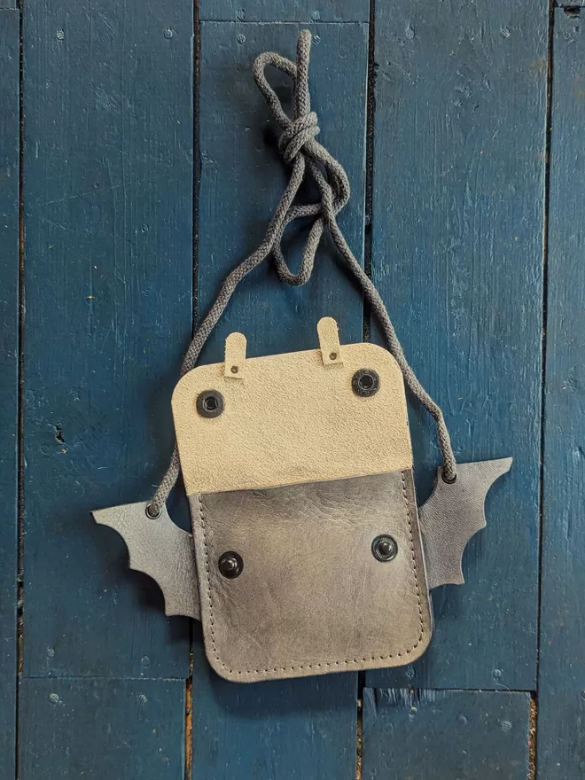 Front view of open handmade leather Bat cross body purse.