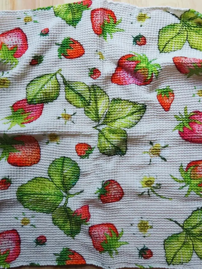 Strawberry Waffle Tea towel, on a wooden table. 