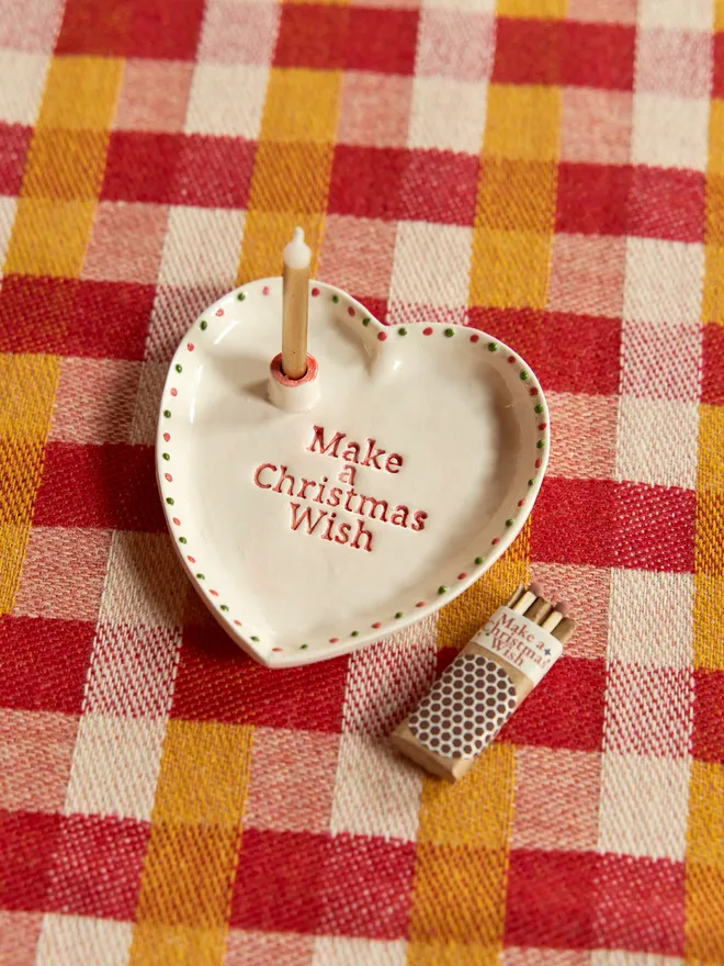 'Make a Christmas Wish' Ceramic heart dish placed on a yellow and red checkered tablecloth ccomes with matches 