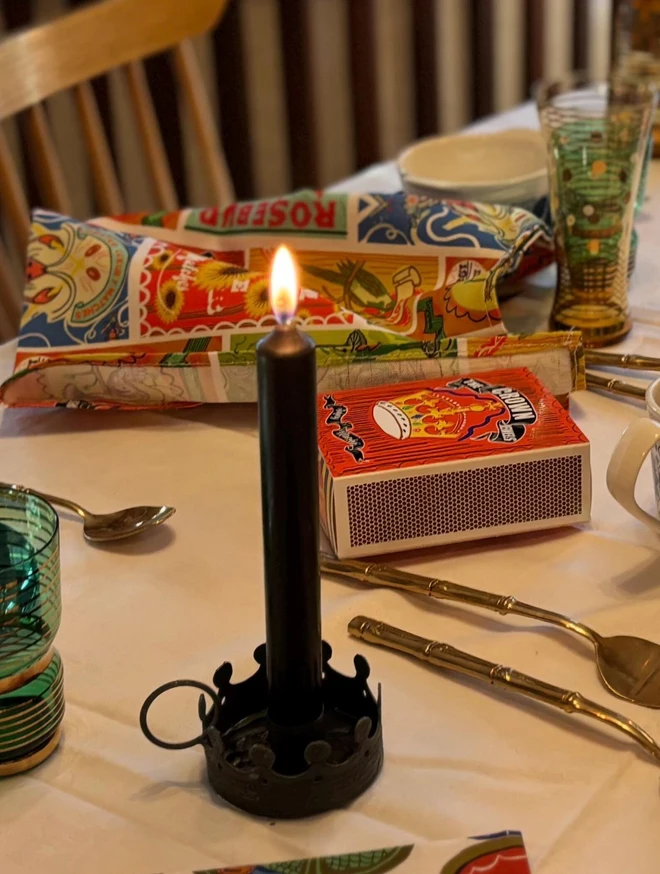The Crown Jewels Matchbox, a red matchbox with a crown design sitting on a decorated surface accompanied by other accessories. 