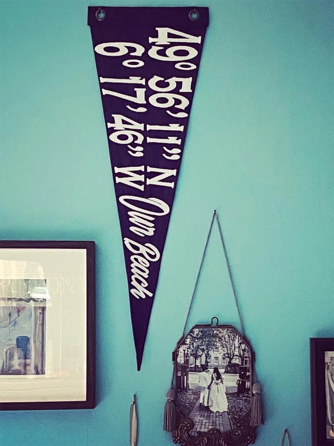 A navy bespoke coordinate pennant flag hung on a wall