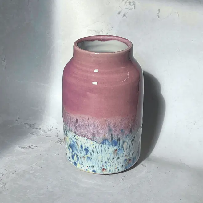 Shoreline Large Vase, a colourful vase placed on a stone surface in front of a plain backdrop. 