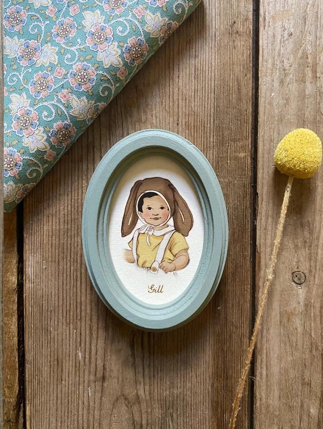 a photograph of a little asian boy Indian boy personalised easter bonnet portrait perfect for a unique easter gift personalised with the Childs name perfect for a nurse or mother or grandmother, framed in a light blue duck egg blue handmade wooden oval frame