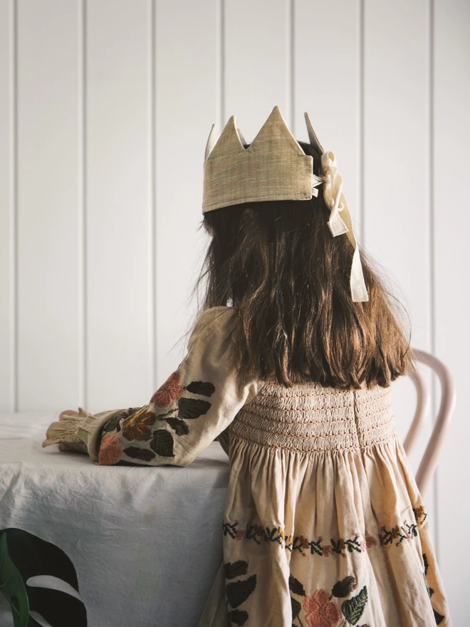 Girl playing at a table with her gold crown on