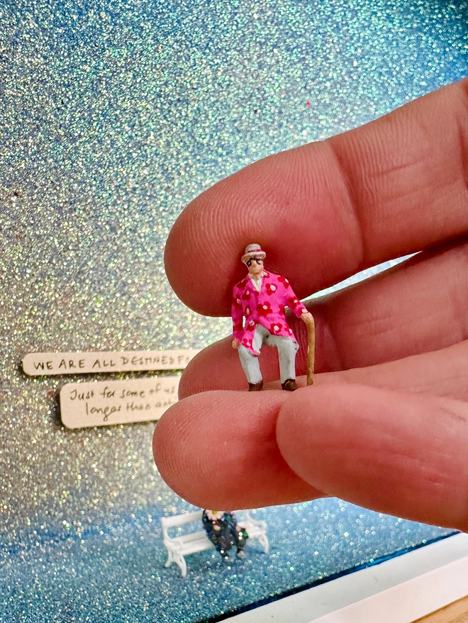 Image showing 1:87 scale of tiny painted old man figure relative to a human hand 