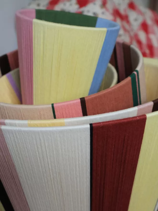 Lifestyle image of a stack of lampshades inside of eachother with quarter colourblock lampshade on the top 