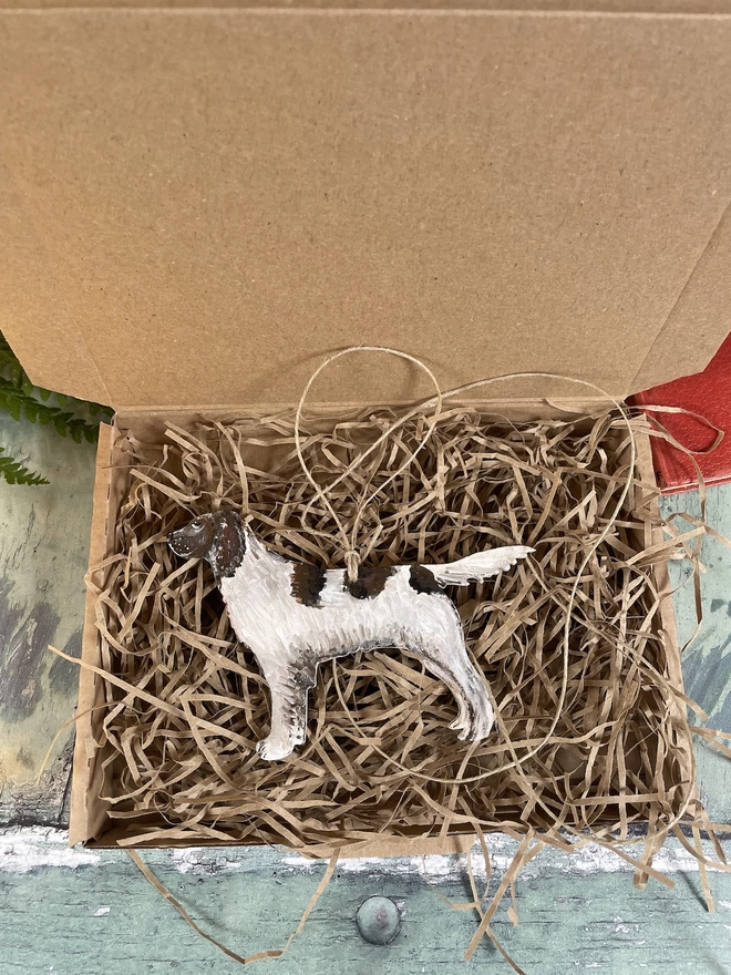 A Springer Spaniel Memory Portrait Decoration being prepared in a packing box with straw