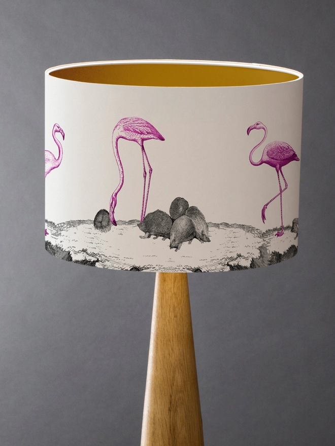 Drum Lampshade featuring pink flamingos and hedgehogs with a gold inner on a wooden base 