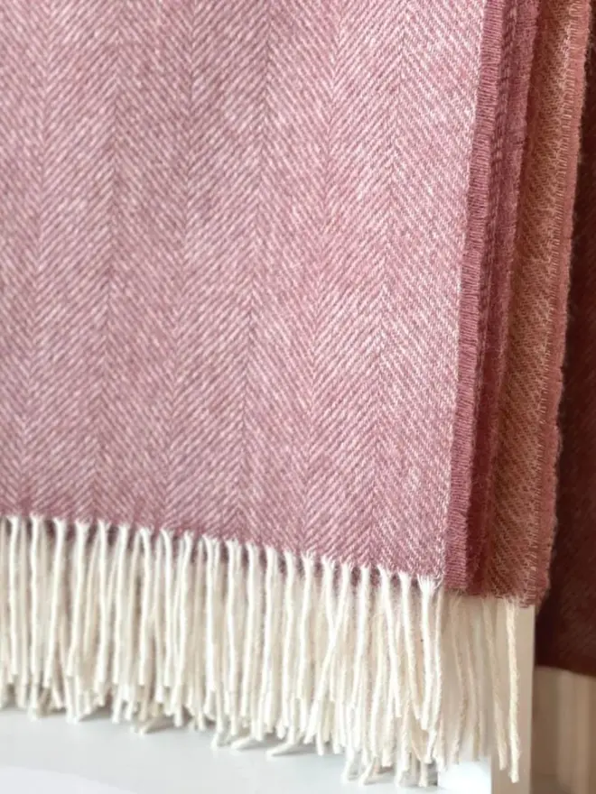 Lambswool dusty pink throw with white tassels.
