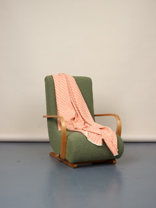 arabella lambswool blanket. a textured pink blanket thrown over a green chair. 