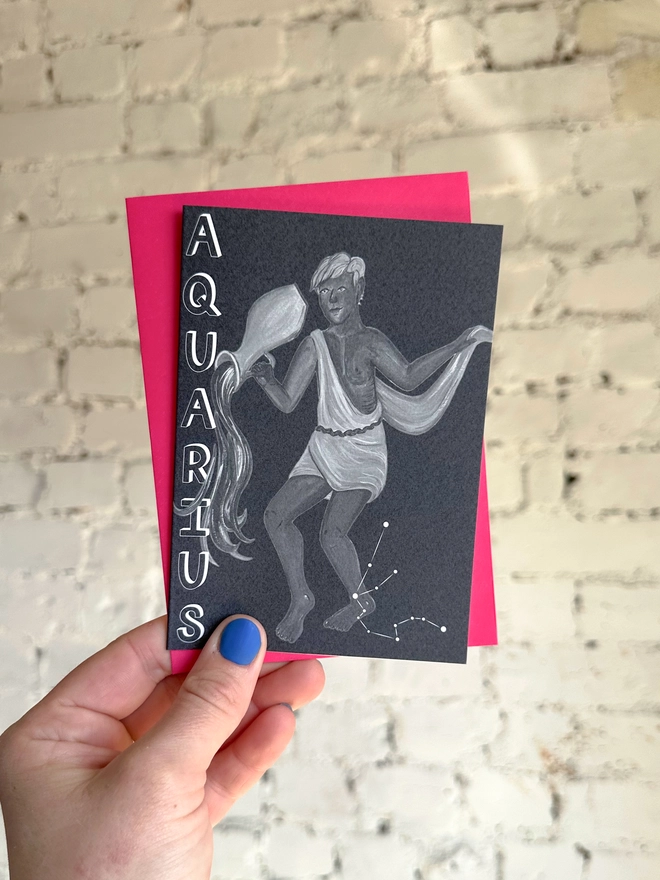 a greetings card featuring a greyscale illustration of a zodiac style water bearer with the text “AQUARIUS” with a neon pink envelope
