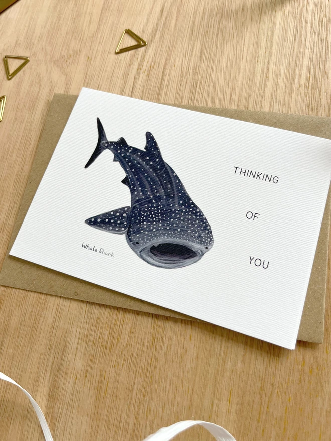 a greetings card featuring an illustration of a whale shark with the text “Thinking of you”