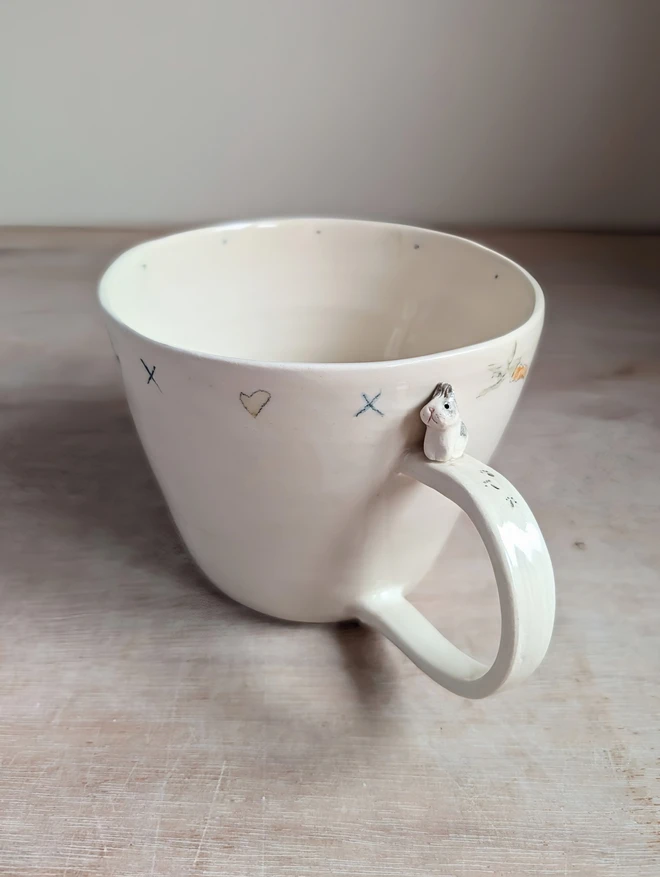 White ceramic cup with miniature bunny on the handle and hand painted carrots, hearts and pawprints