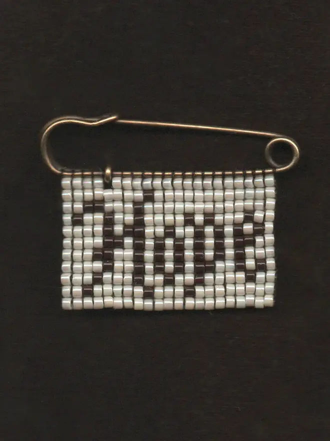 'lingua vi' beaded 'hope' pin. a beaded pin badge with 'hope' written on a pearl background.