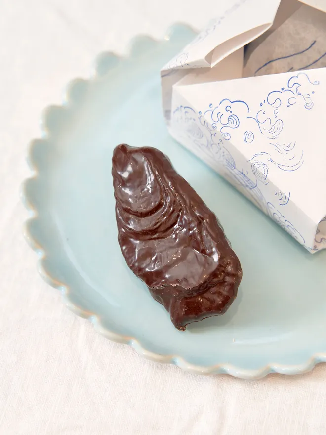 chocolate oyster on blue plate, with white box