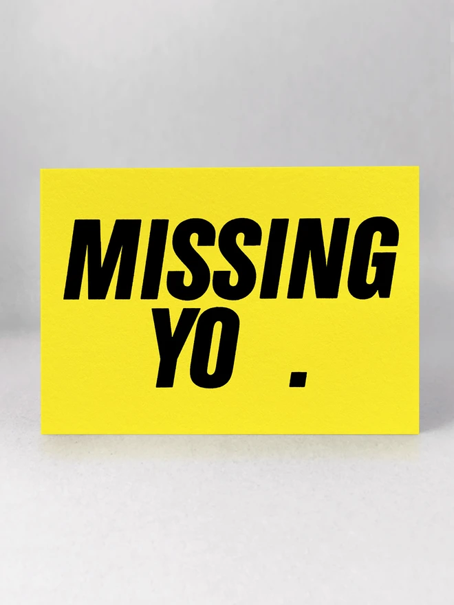 Bright yellow card with the words Missing you and a full stop screenprinted in black. There is a gap where the letter u shoud beissing