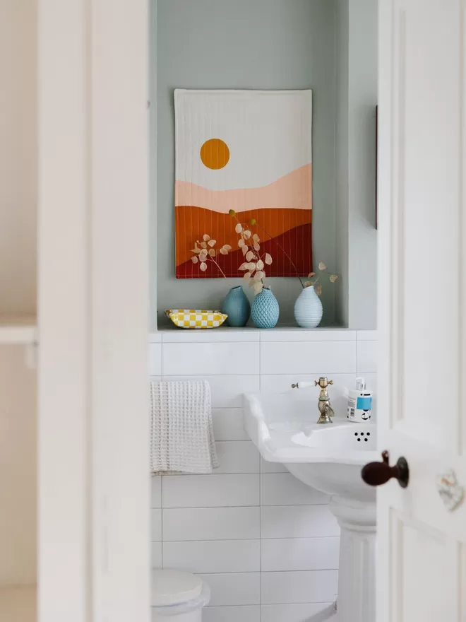 Earth Quilt Hanging On Blue Wall In Bathroom