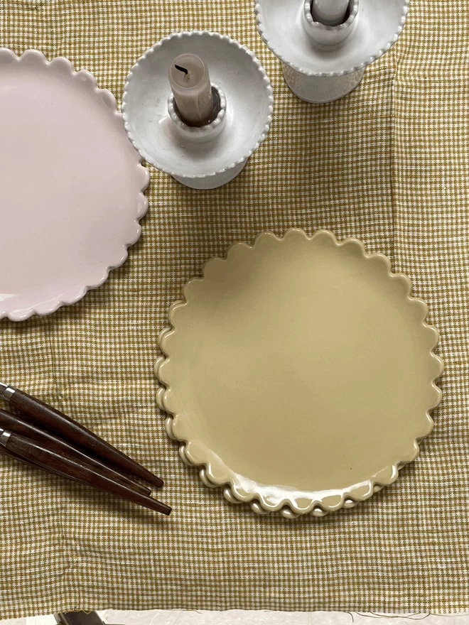 a dijon yellow and blossom pink daisy edge plate on a tablesetting with candlestick and cutlery