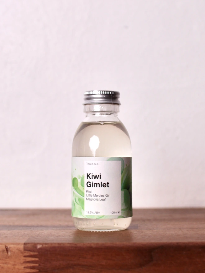 Mini Kiwi Gimlet bottle sitting on a wooden shelf