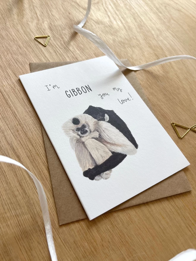 A greetings card featuring two gibbons sat side by side with the phrase “I’m gibbon you my love”