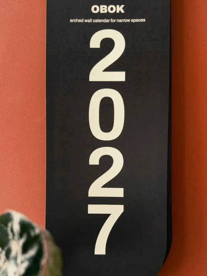 Obok 2027 Arched Wall Calendar cover, on a red wall.