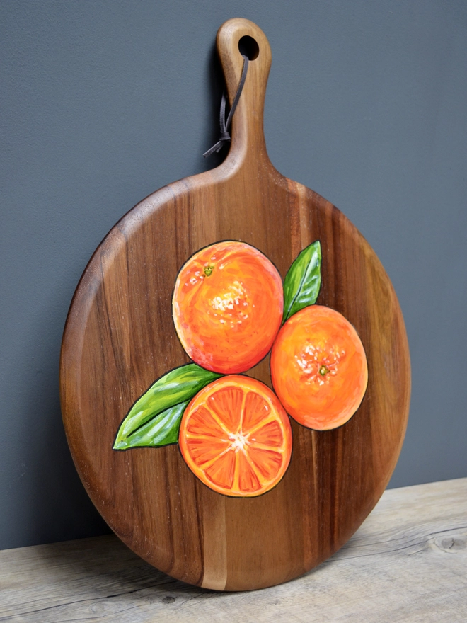 Wooden serving board with a handpainted design of some clementines