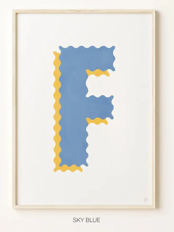 Framed wall art print featuring a large decorative letter “F” in blue tones with a ric rac–style wavy edge design, centered on a white background. 