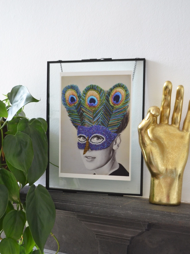Black and white photograph print, woman wearing embroidered peacock mask in frame