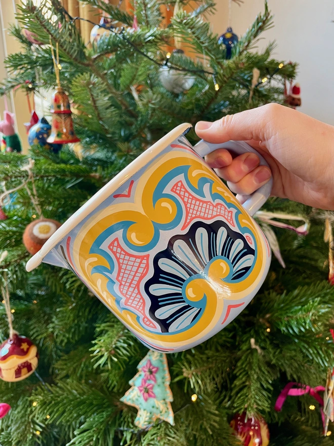 Blue enamel jug hand painted with a fairground design in blue, pink and yellow