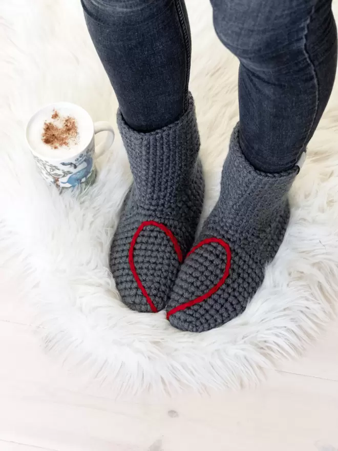 Grey socks with a red heart showing as feet stand together
