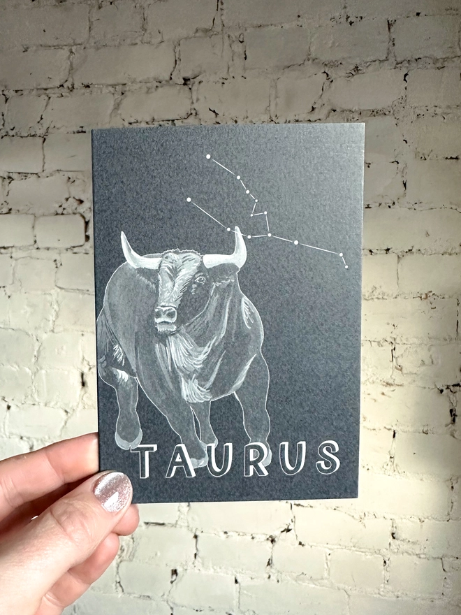 a greetings card featuring a greyscale illustration of a zodiac style bull with the text “TAURUS”