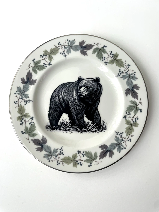 a vintage plate with an ornate border, in the centre of the plate is a vintage style black and white illustration of a big bear