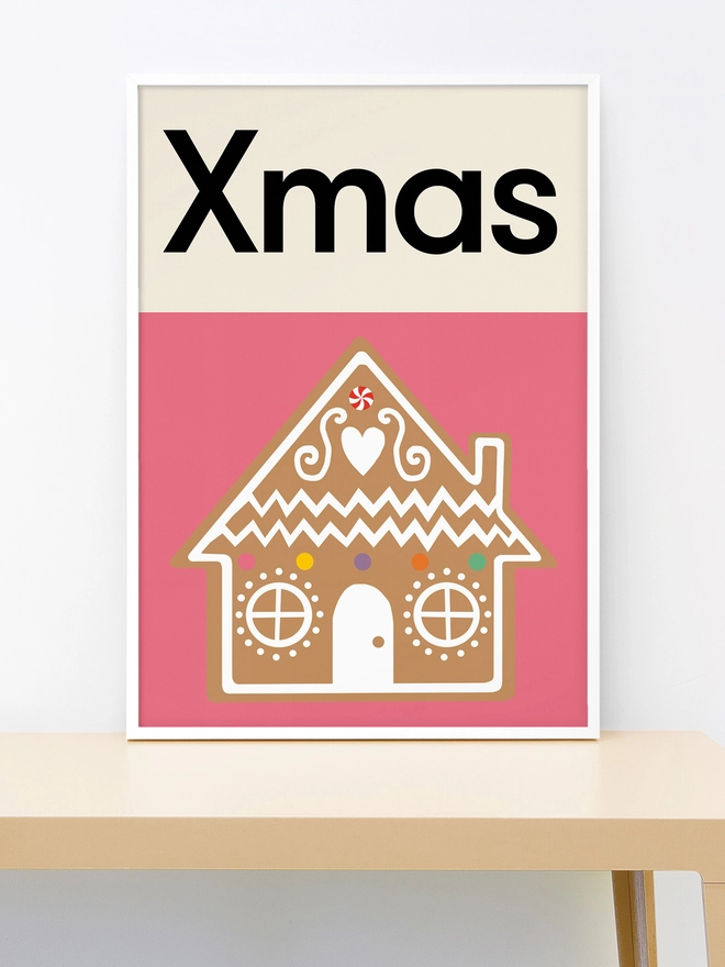 Framed wall print of an illustrated gingerbread house on pink background