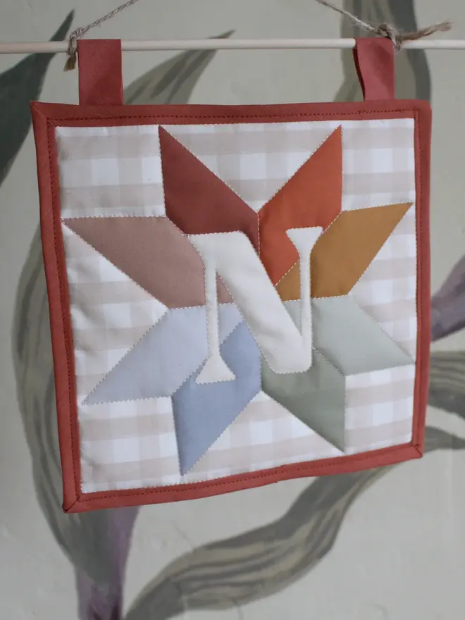 personalised initial quilt hanging. a hand-sewn hanging quilt with a star design in the centre, alongside the initial 'N'.