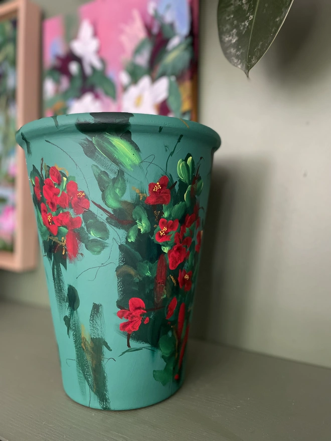 Hand painted tall deep green plant pot adorned with bright red quince flowers