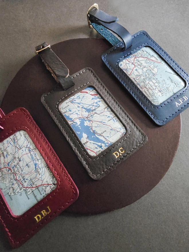 a red brown and blue leather luggage tag featuring a section of a original silk war escape map