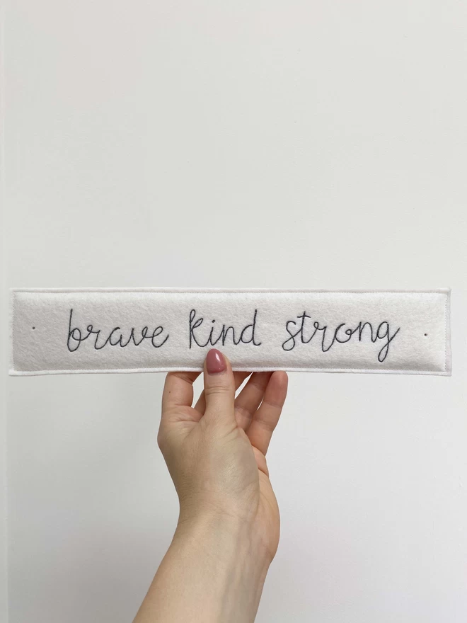Brave Kind Strong Felt Embroidered Sign in a hand