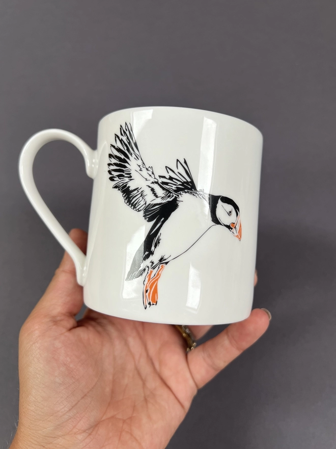 The reverse of the mug showing a puffin with his wings up coming in for a landing