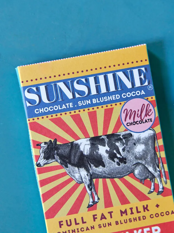 the milker milk chocolate bar. packaging for a chocolate bar featuring an illustrated cow and vibrant red and yellow colours.