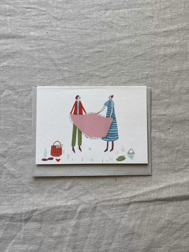 greetings card with 2 people having a picnic on it.