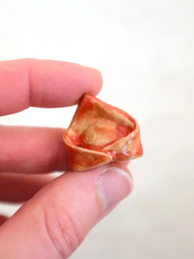 ceramic pasta magnet. a ceramic tortellini magnet photographed close up.