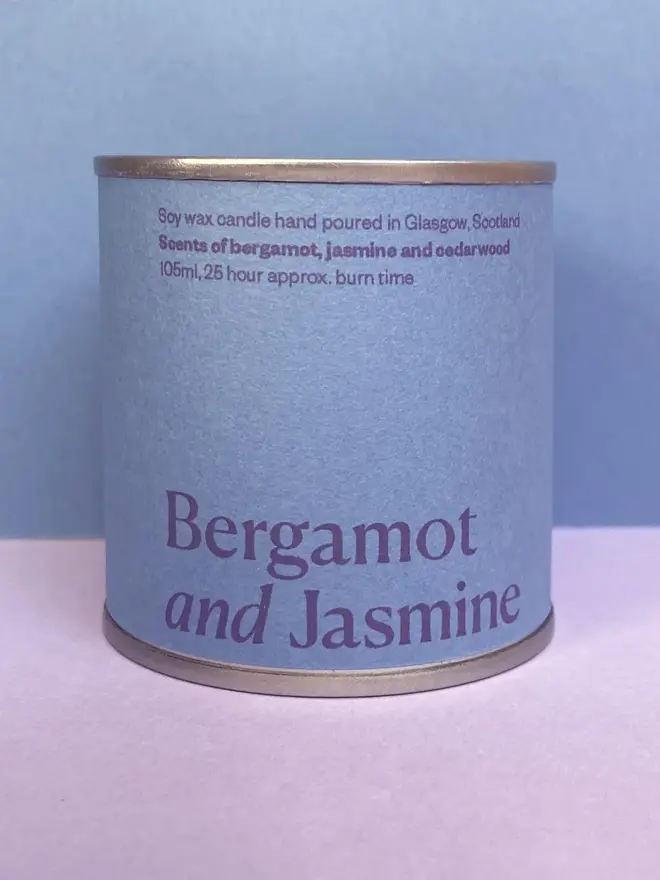 Bergamot & Jasmine Soy Wax Candle Tin against a purple and blue background. 
