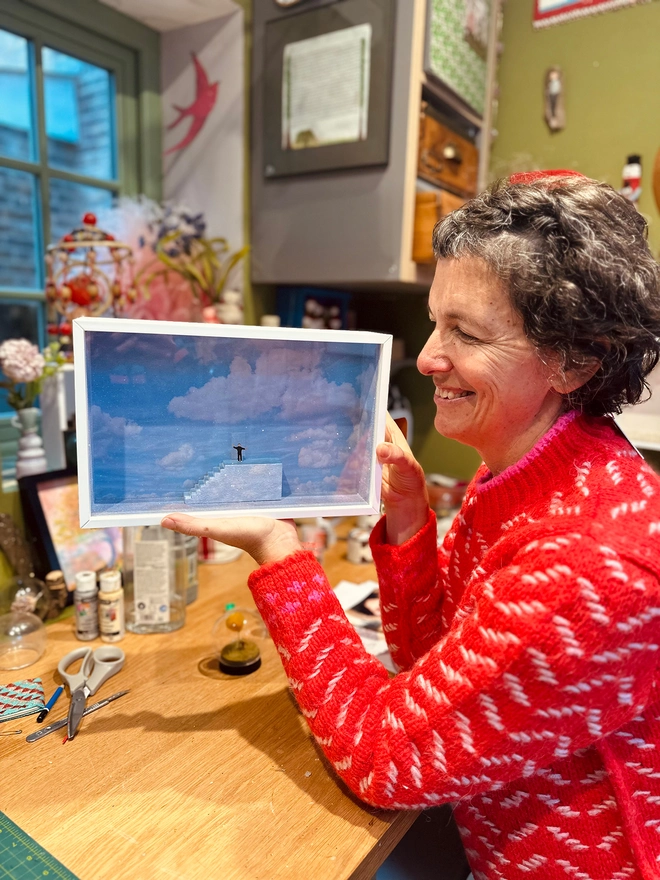 Artist Lisa Swerling in her London studio holding diorama of The Truman Show