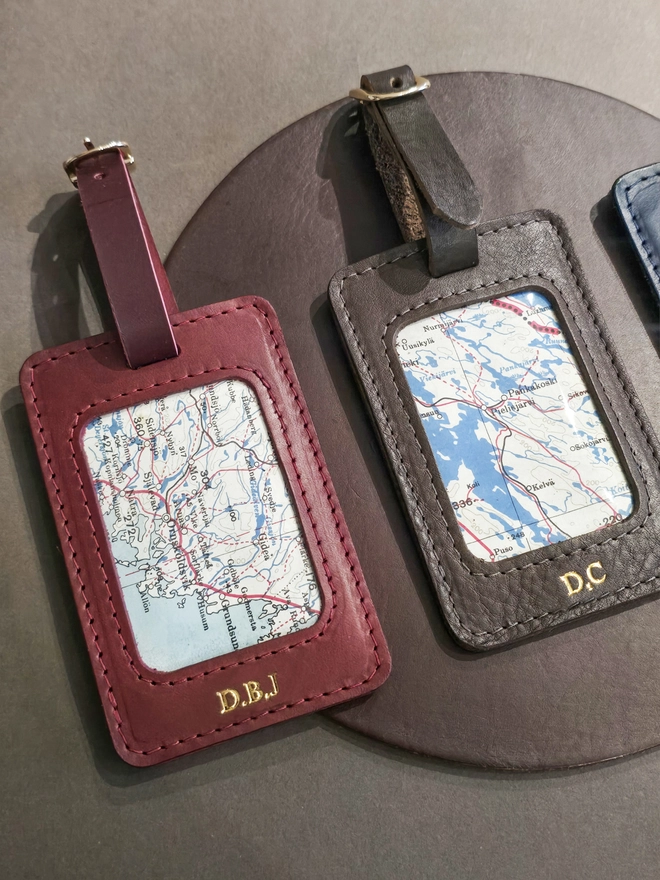 a red and brown leather luggage tag with a gold buckle featuring a section of a original silk war escape map 